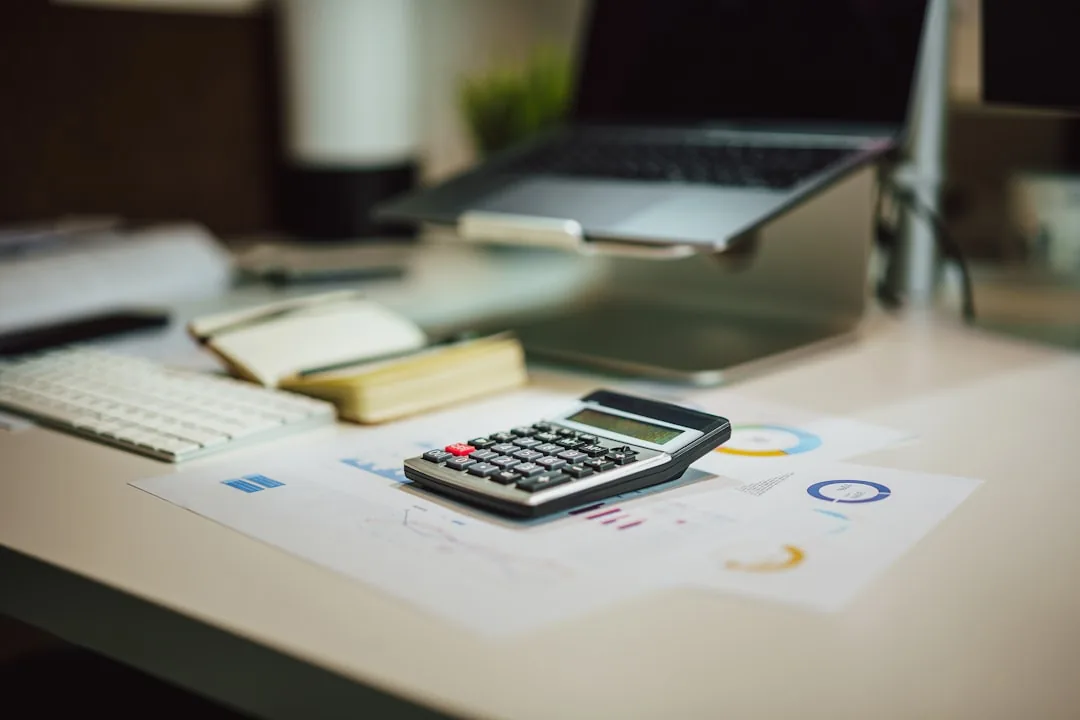 Calculatrice, graphiques et carnet posés sur un bureau pour évaluer un placement